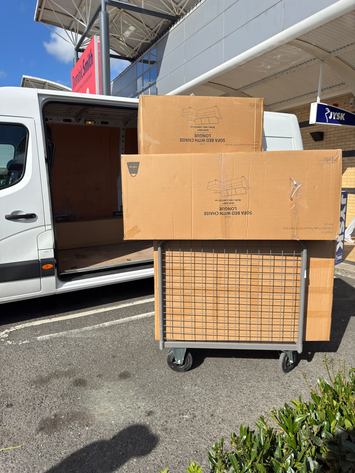 New boxed furniture being collected beside a van